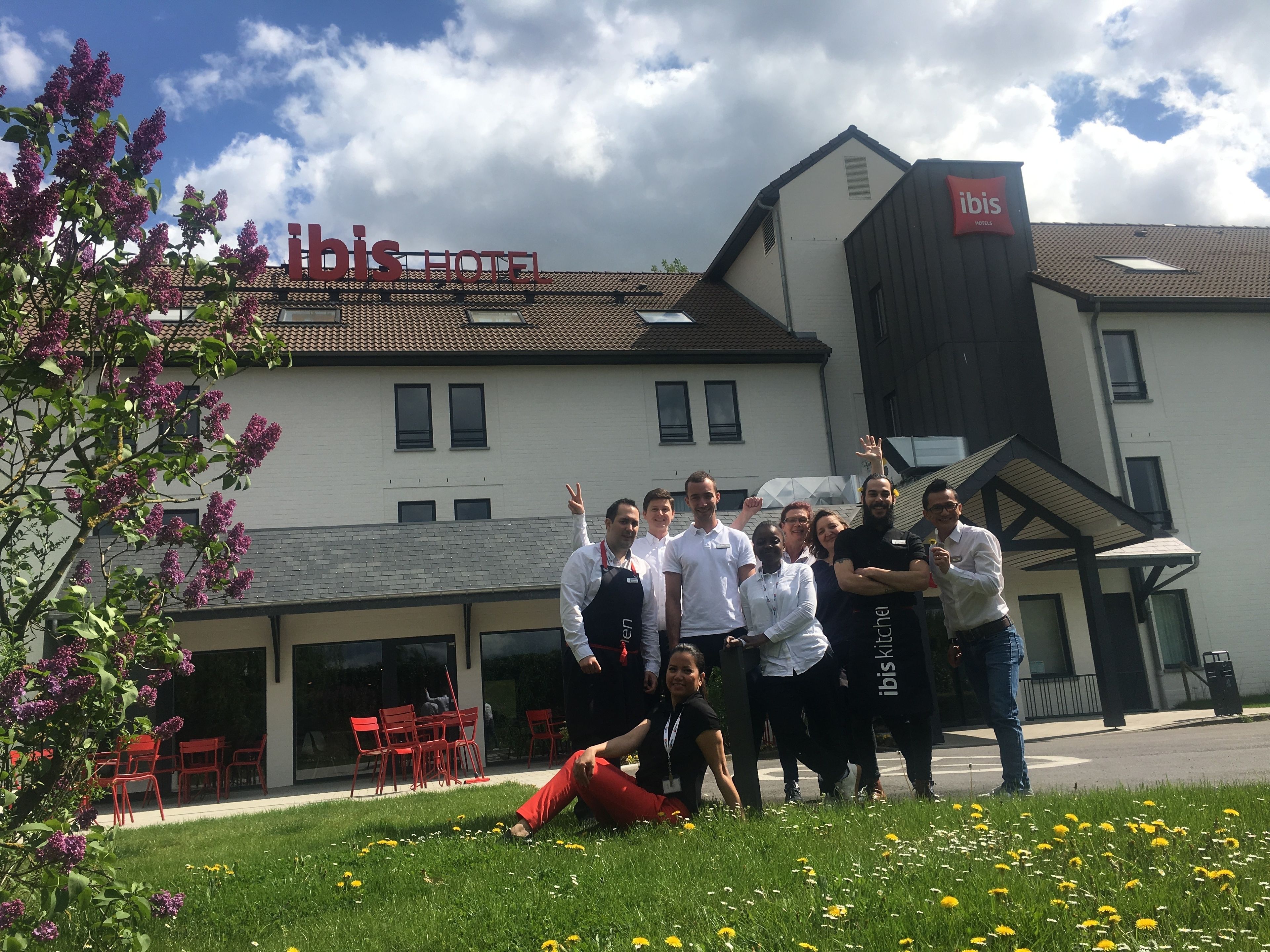 Un grupo de personas frente a un hotel con un cartel que dice "ibis HOTEL".
