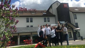 Un grupo de personas frente a un hotel con un cartel que dice "ibis HOTEL".