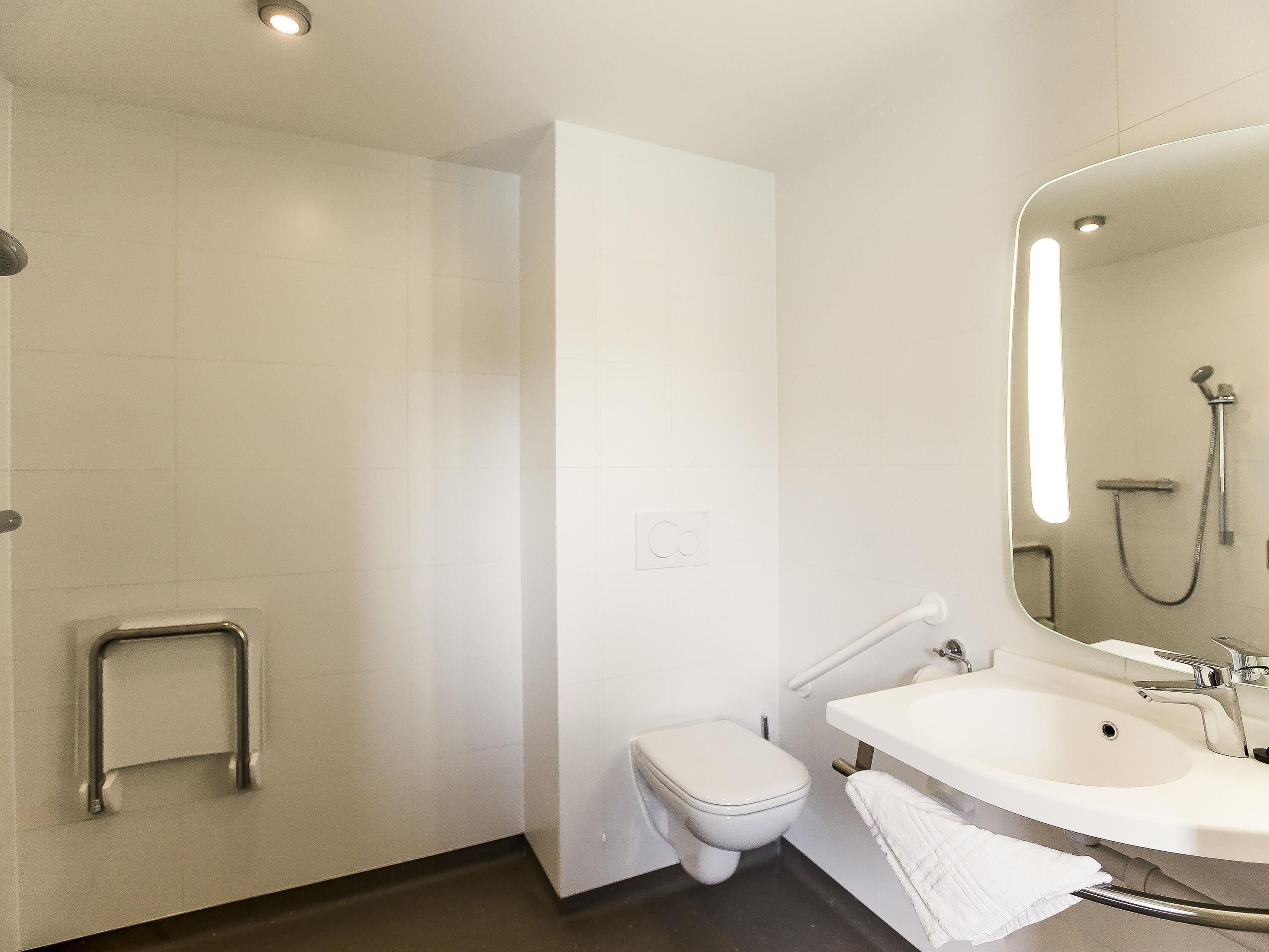 Une salle de bain moderne équipée de toilettes, d’une douche et d’un lavabo.