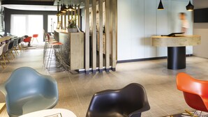 Un interior moderno con un mostrador de recepción curvo, zona de bar y asientos con sillas de colores.