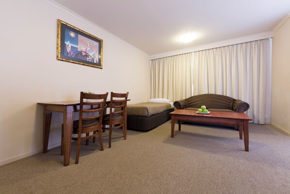 A small, furnished room with a desk, two chairs, a sofa, and a coffee table. - Best Western Plus Canberra Central Apartments (Dickson)