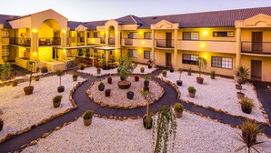 A hotel courtyard with multiple balconies, potted plants, and a central circular garden. - Best Western Plus Canberra Central Apartments (Dickson)