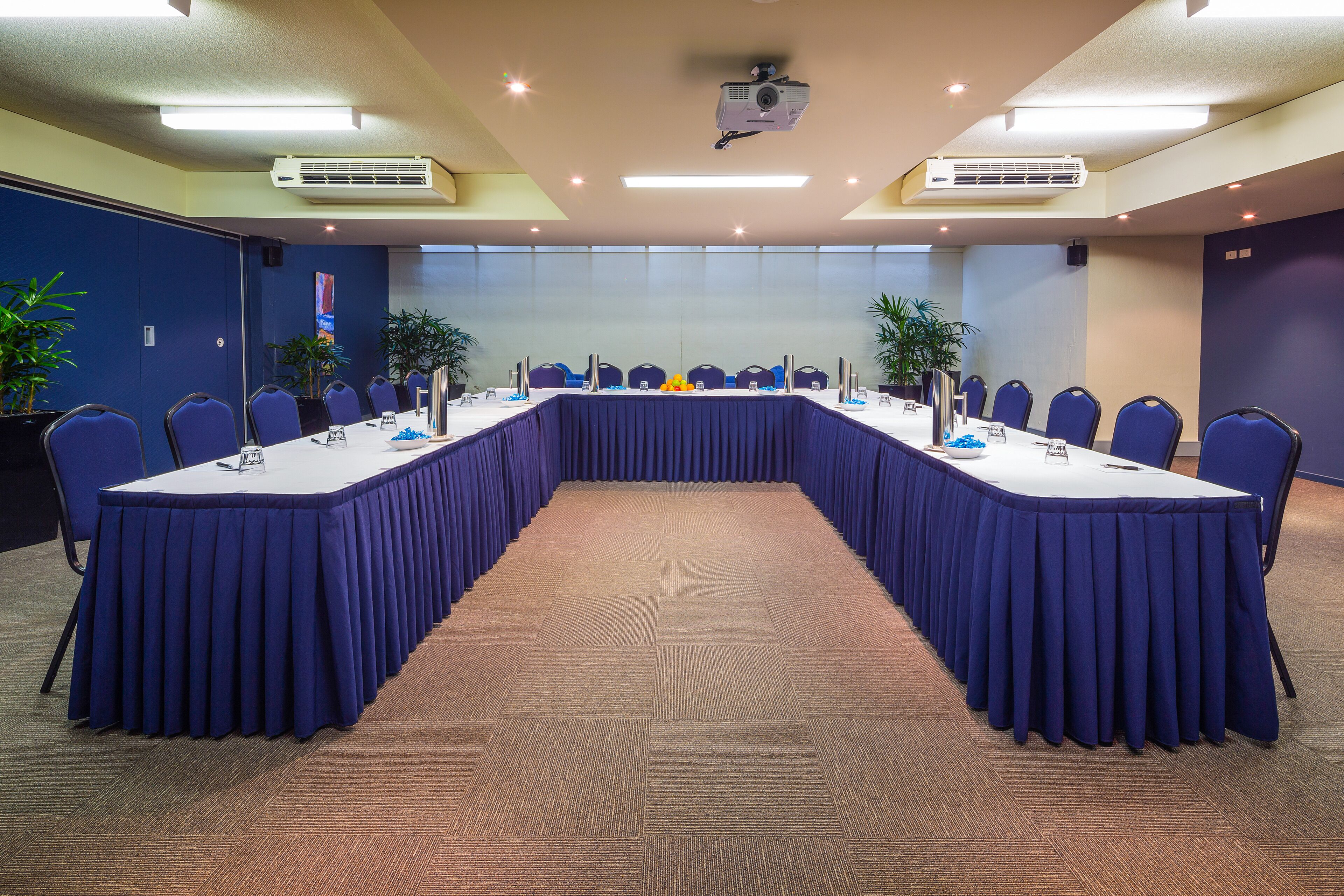 A conference room with a long table, chairs, and a projector.