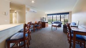 A modern living room with a dining area, a sofa, a TV, and a laptop on a table. - Best Western Plus Canberra Central Apartments (Dickson)