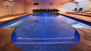 A large indoor swimming pool with a tiled floor and a wooden deck surrounding it. - Best Western Plus Canberra Central Apartments (Dickson)
