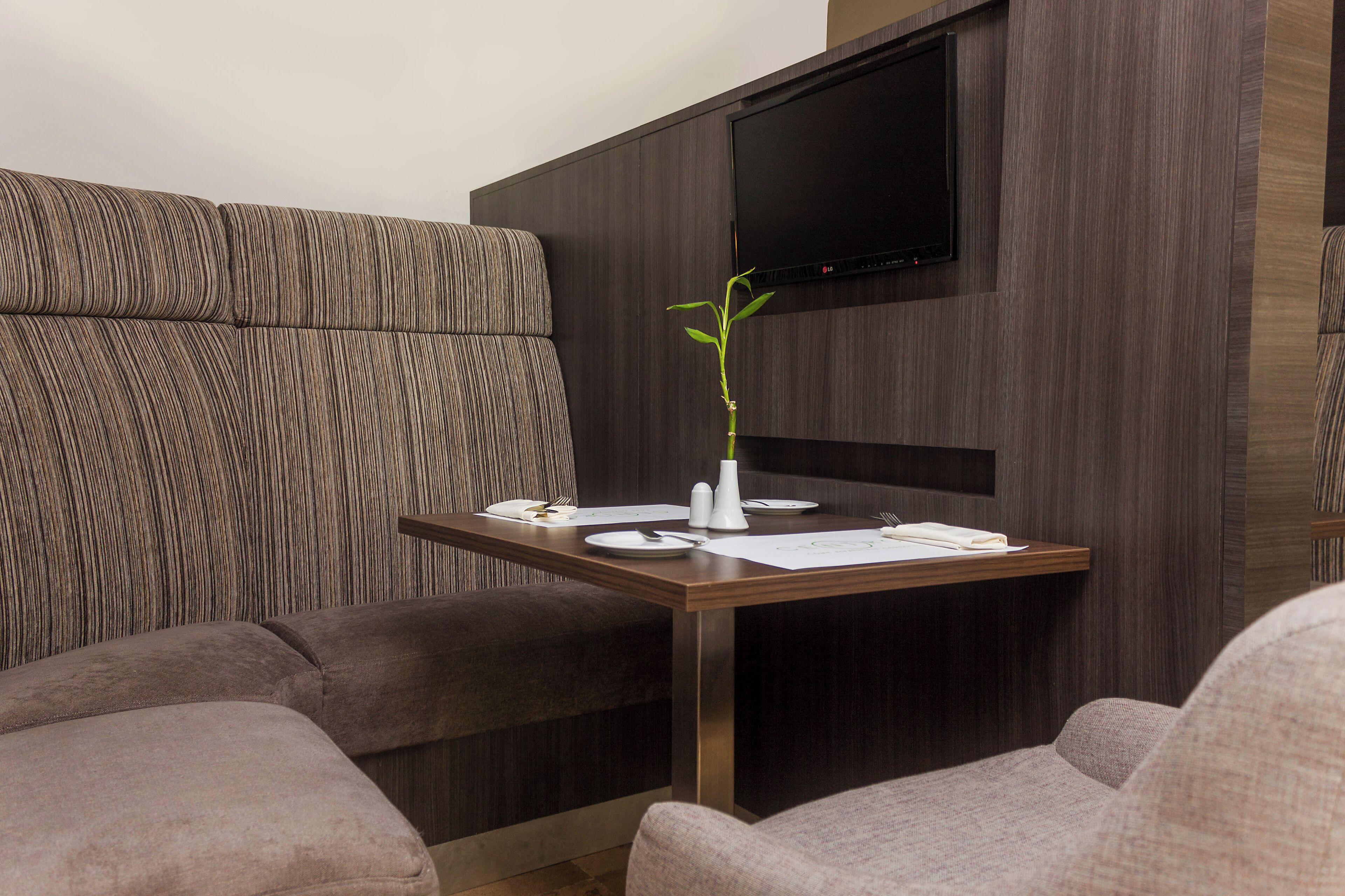 Una habitación moderna con un sofá, una mesa de comedor con platos y cubiertos, y un televisor de pantalla plana montado en la pared.