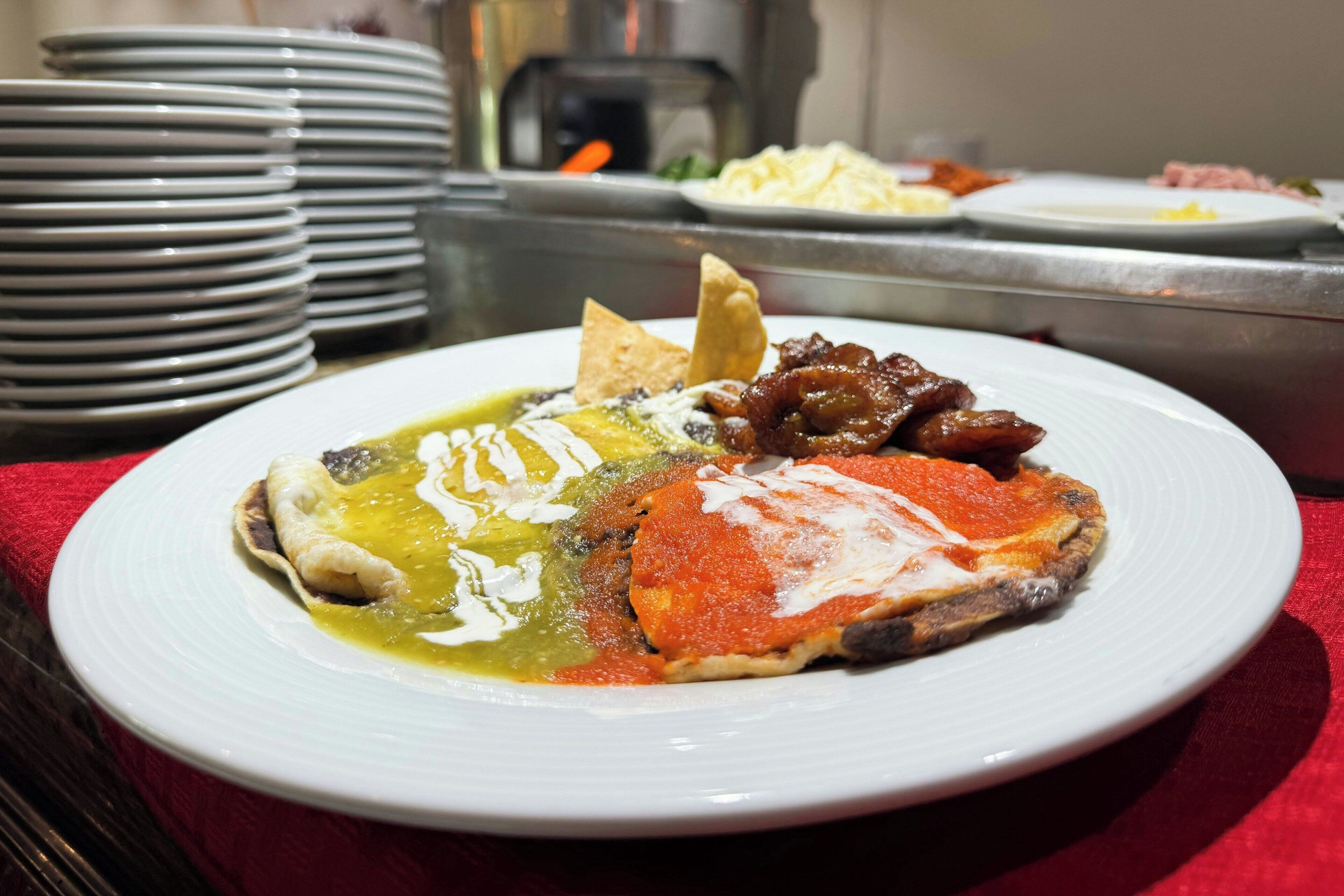 A plate of food with various toppings, including a red sauce and a green sauce, on a white plate.