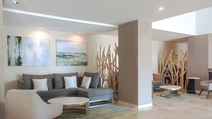 Una sala de estar moderna con un sofá modular, sillones, una mesa de centro y arte abstracto en la pared.
