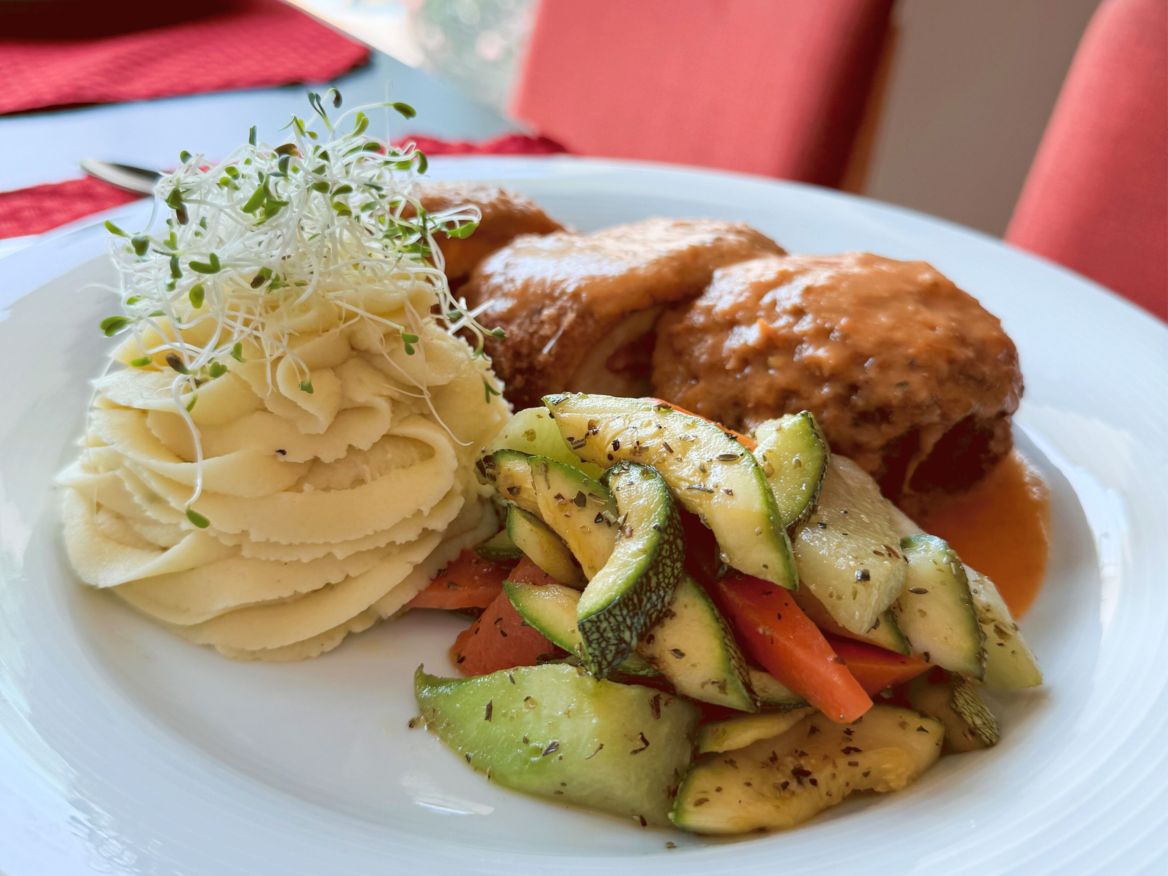 Une assiette comprenant un plat de viande, de la purée de pommes de terre et un mélange de légumes.