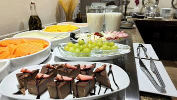 A buffet with various food items including chocolate desserts, grapes, and other fruits.