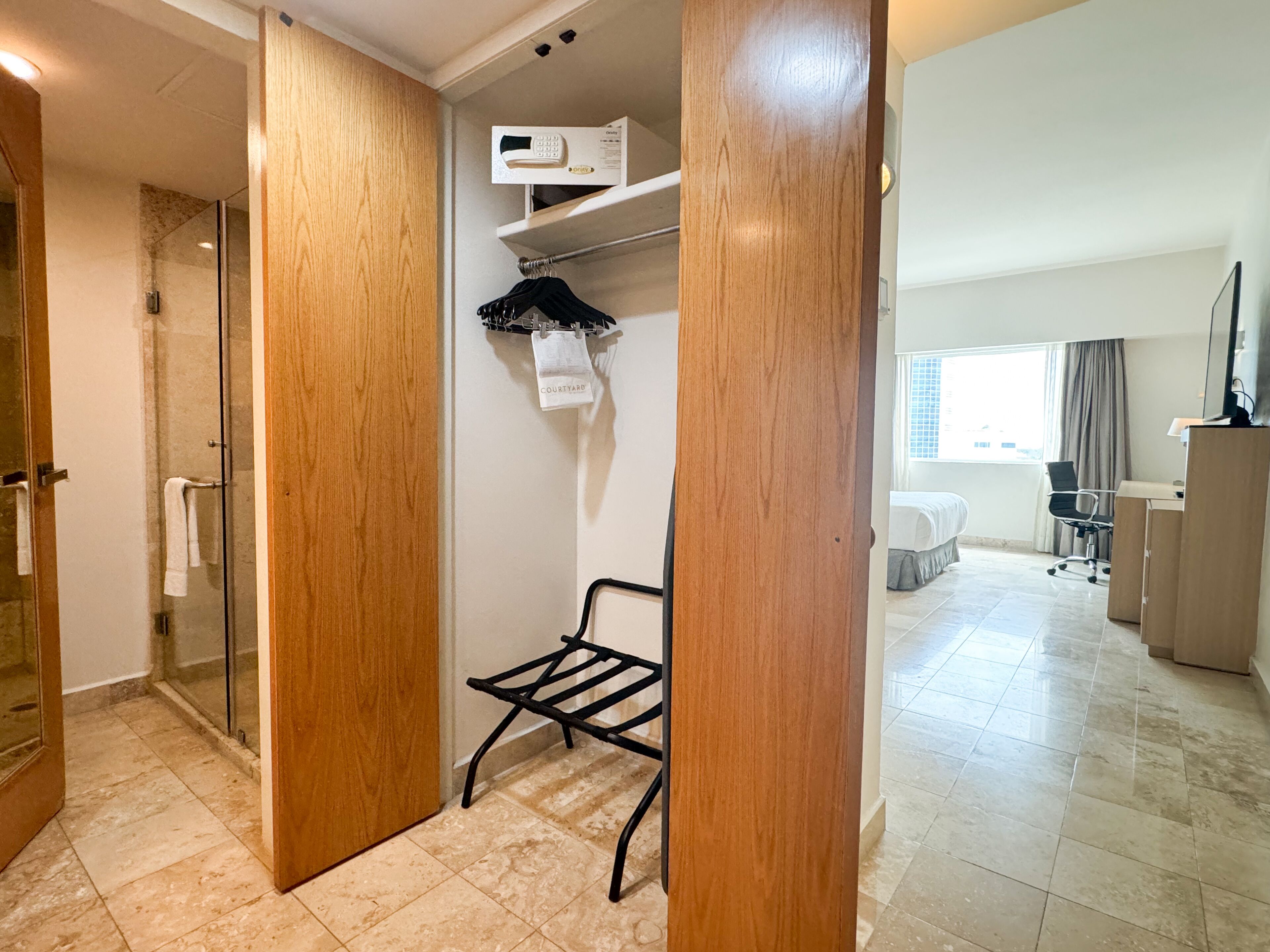 Una habitación de hotel con ducha, un espacio de descanso pequeño, un escritorio y una cama.