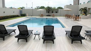 Alberca al aire libre, sombrillas en la alberca y camastros