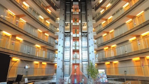 Hotelinterieur met meerdere verdiepingen, een centraal atrium, glazen balustrades en een receptiebalie onderaan.