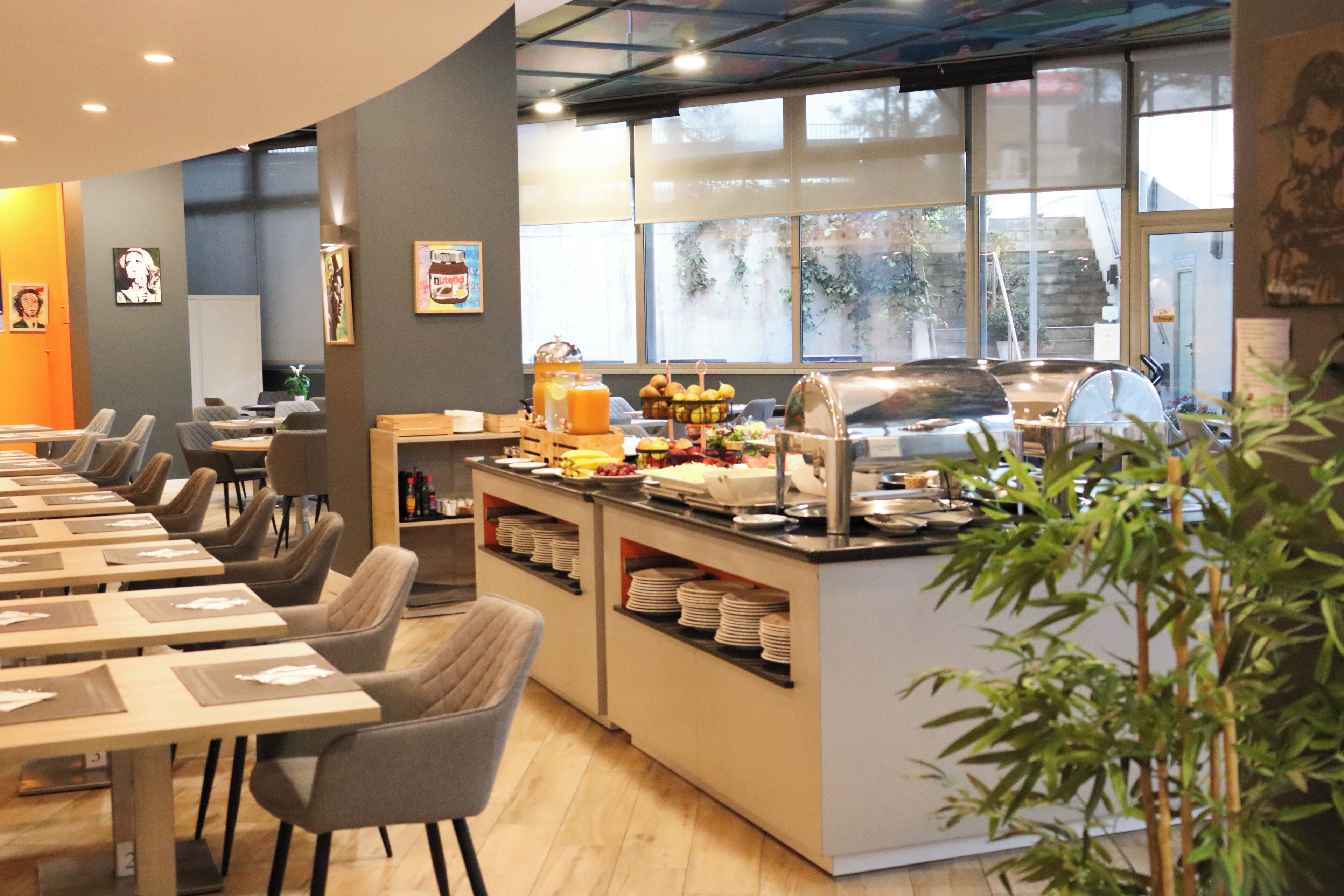 Un restaurante moderno con zona de bufé, disposición de mesas y ventanas amplias.