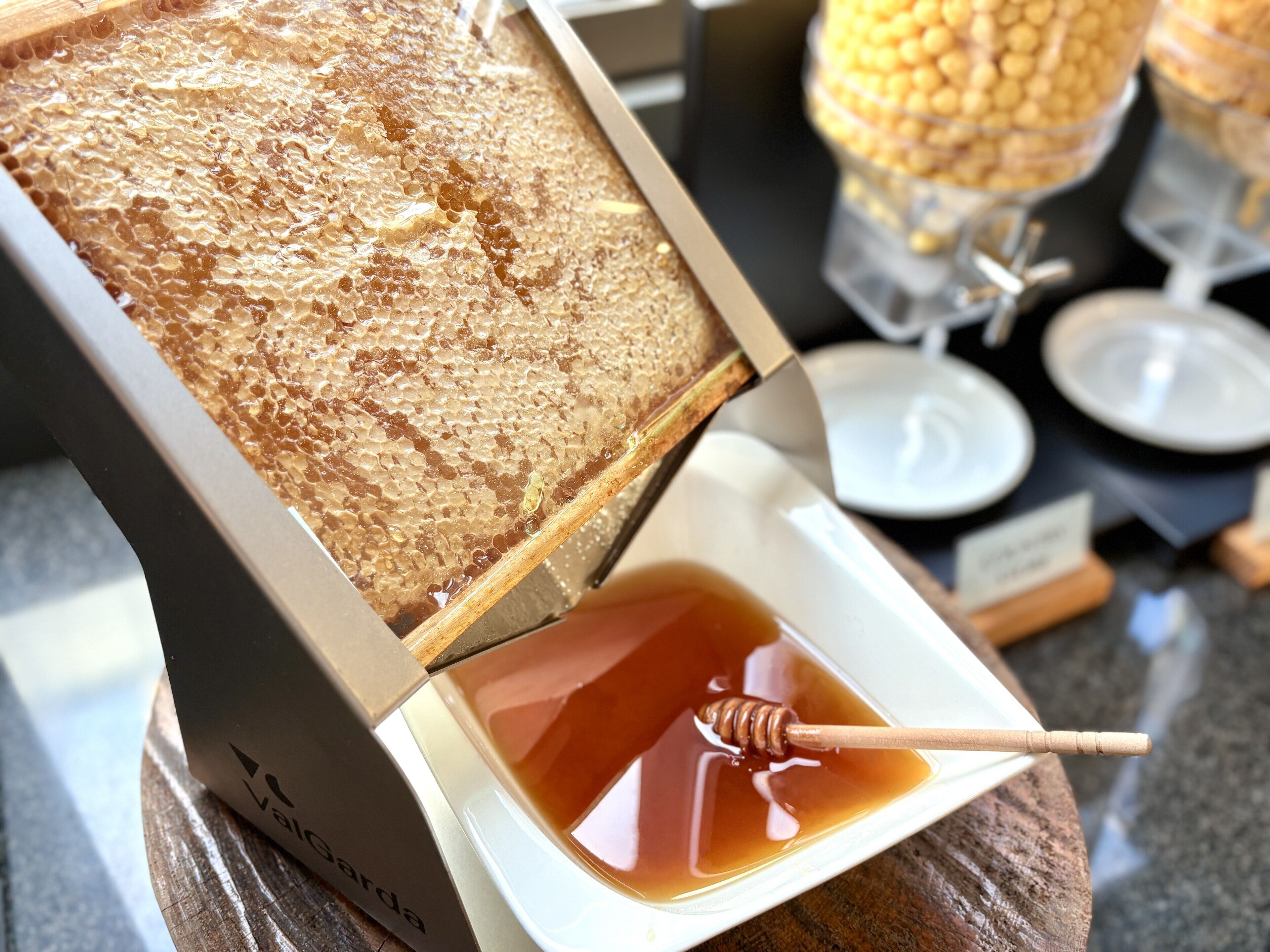 A honeycomb box with honey and a honey dipper.