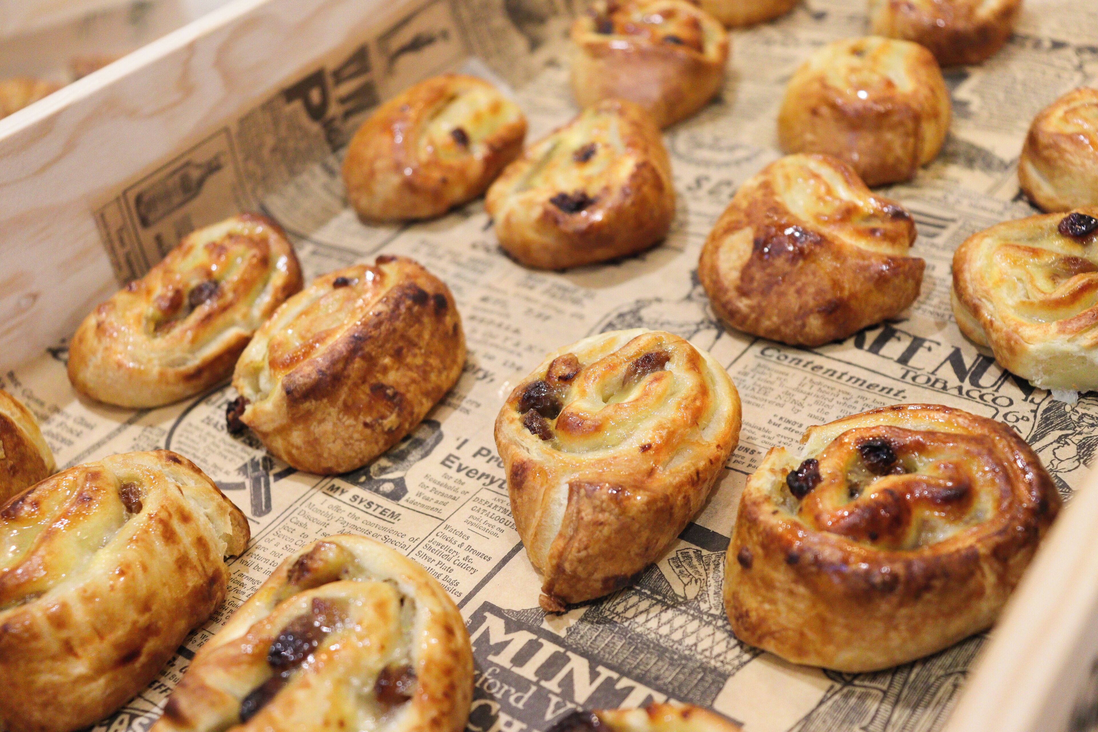 A tray of freshly baked pastries on newspaper paper.