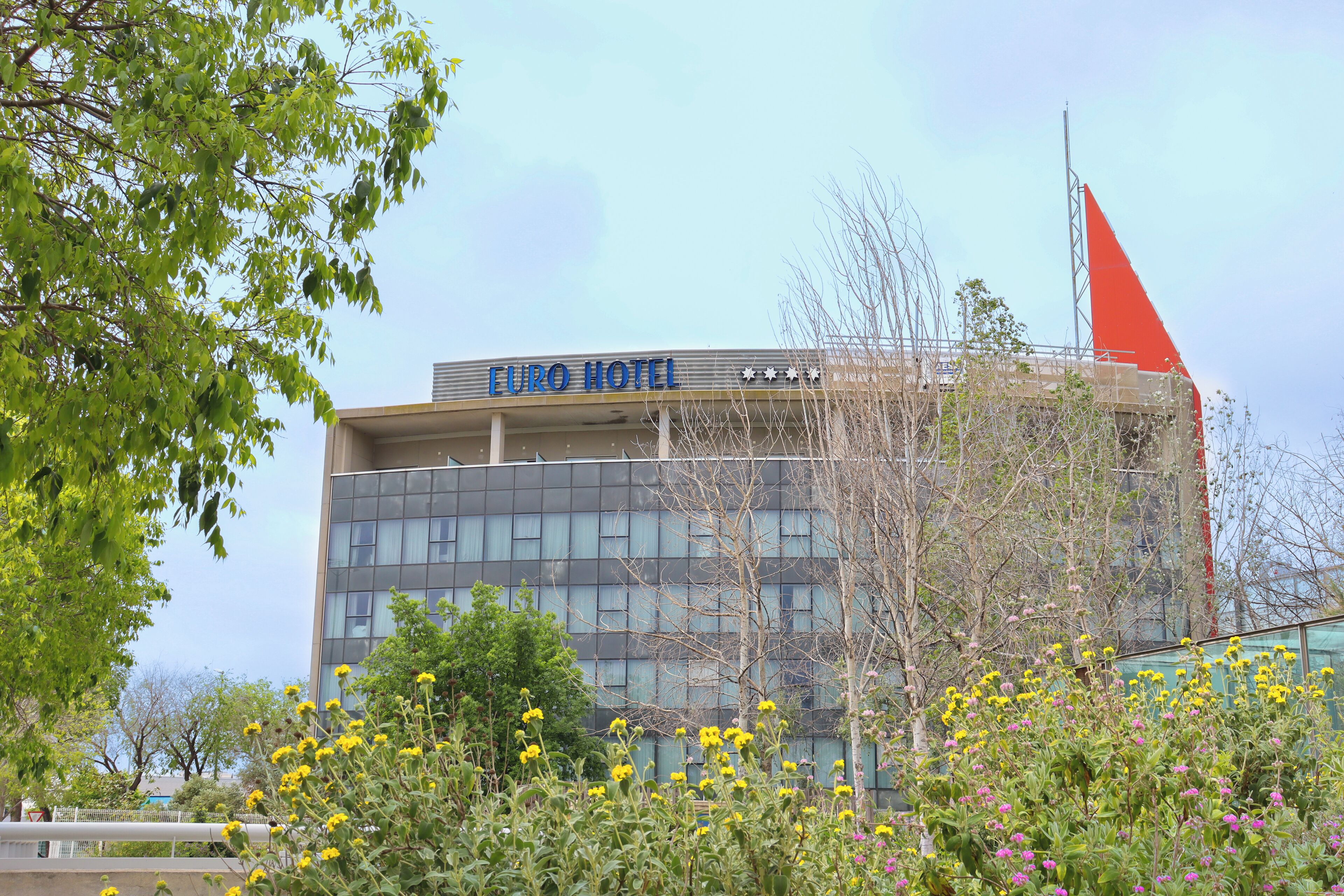 Un hôtel doté d’une façade moderne, d’une enseigne « Euro Hotel » bien visible et d’un mât pour drapeau.