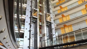 Een meerhoog gebouw met een modern architectonisch ontwerp, voorzien van balkons met glazen hekwerk en een centraal atrium met trappenhuizen.
