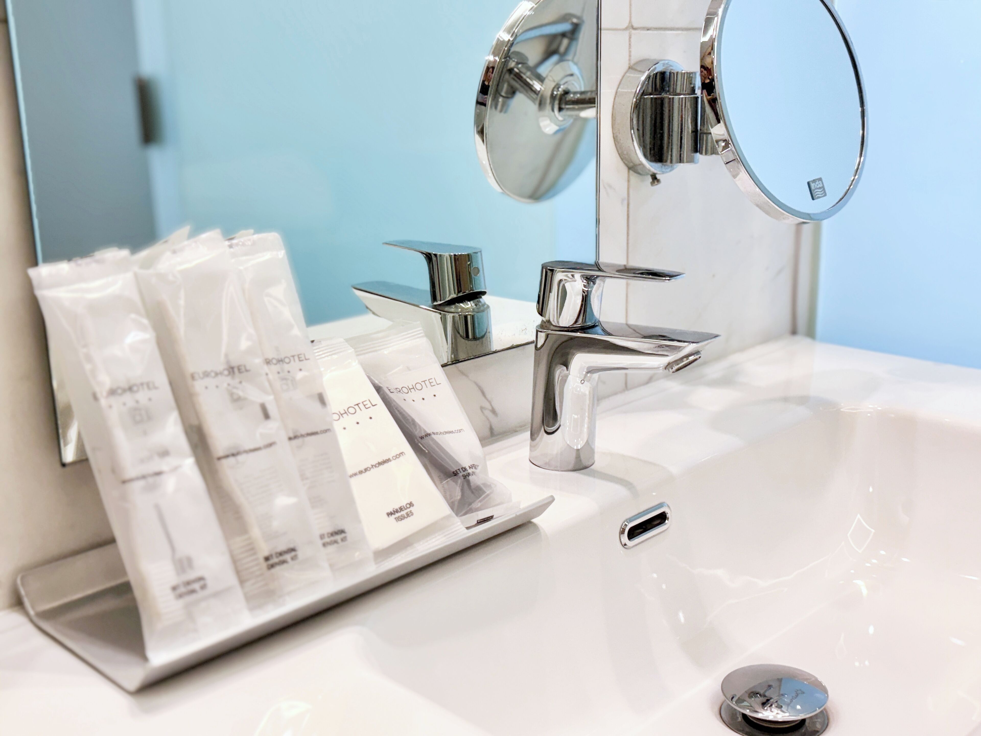 Un lavabo de salle de bain avec un robinet chromé, un miroir et des articles de toilette disposés sur un plateau.