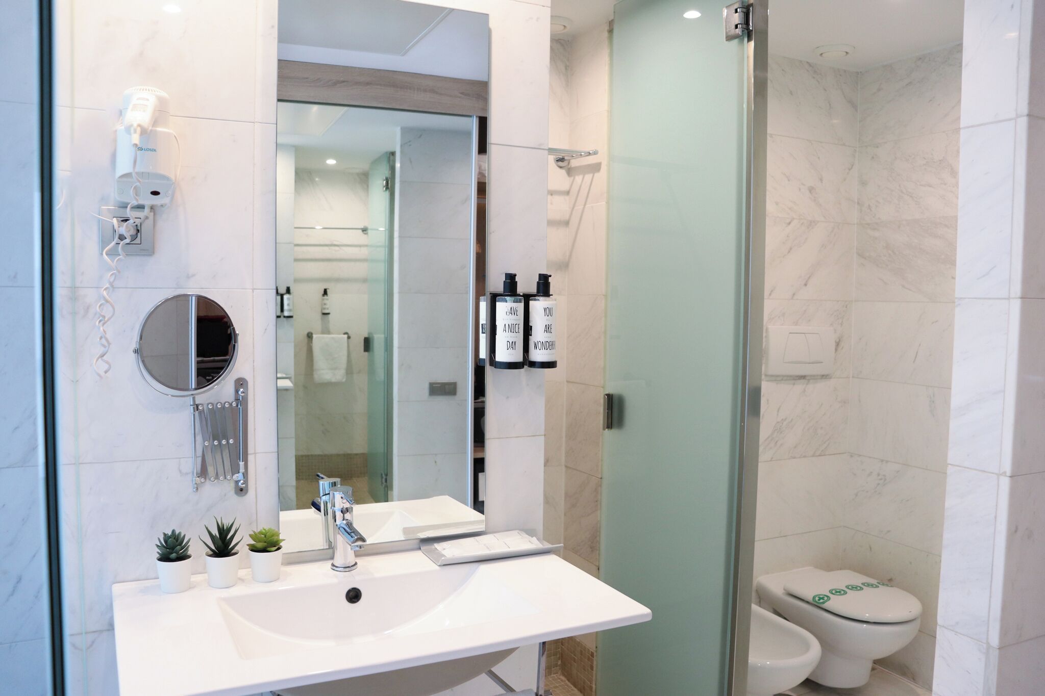 A modern bathroom with a white sink, mirror, and glass shower enclosure.