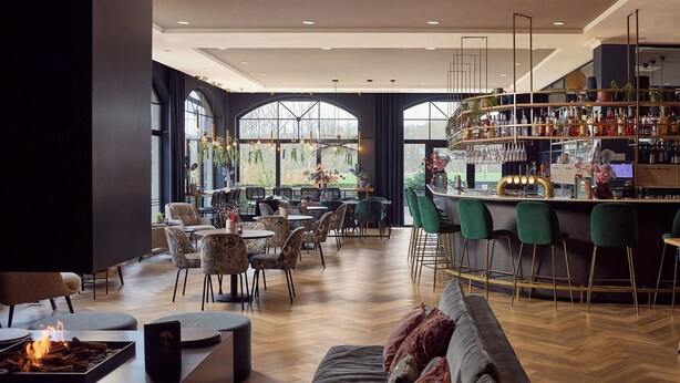 A modern bar area with a curved counter, green bar stools, and a variety of bottles and glasses. - Van Der Valk Hotel Melle - Osnabrück (Melle)