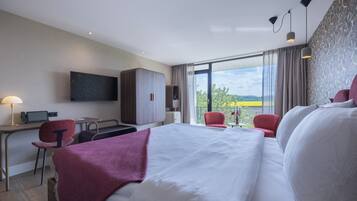 Een hotelkamer met een groot bed, een bureau, een stoel en een aan de muur bevestigde televisie.