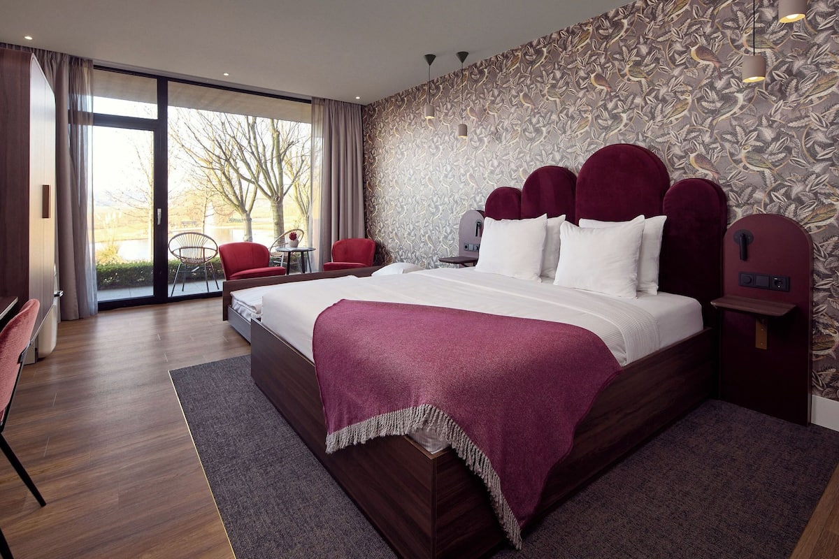 A modern hotel room with a large bed, a desk, and a chair.