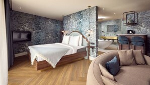 A modern bedroom with a bed, a sofa, a vanity, and a bathtub. - Van Der Valk Hotel Melle - Osnabrück (Melle)