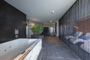 Une salle de bain moderne avec une grande baignoire, une plante en pot et un design épuré.