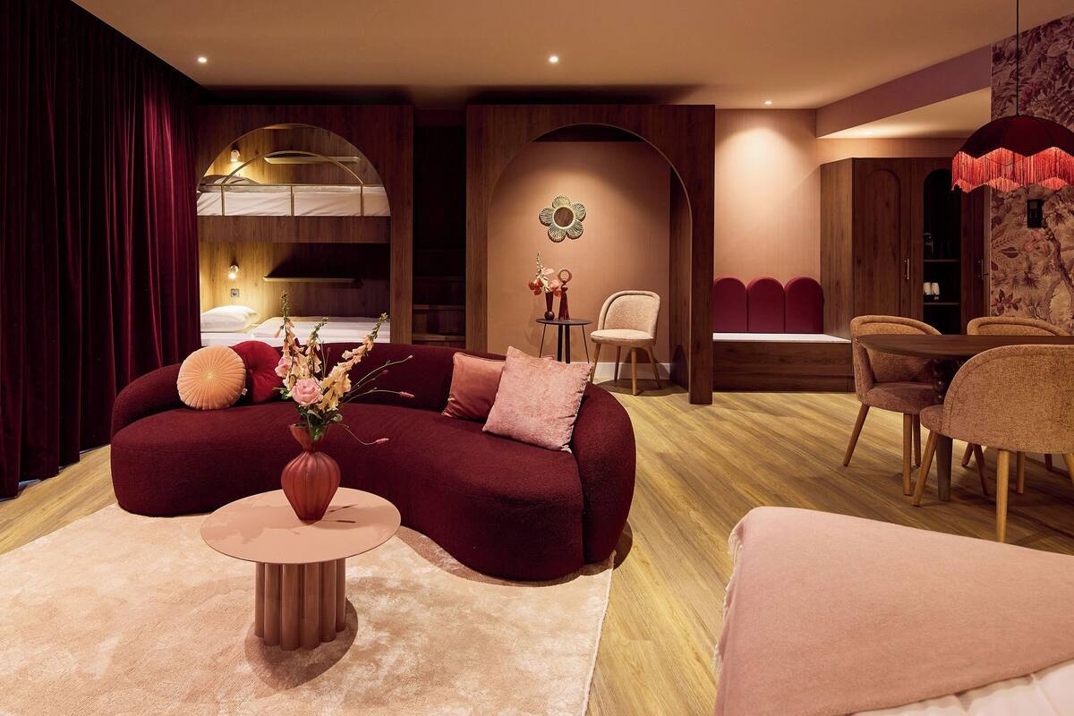 A modern living room with a sofa, a small table, and a dining area with chairs.