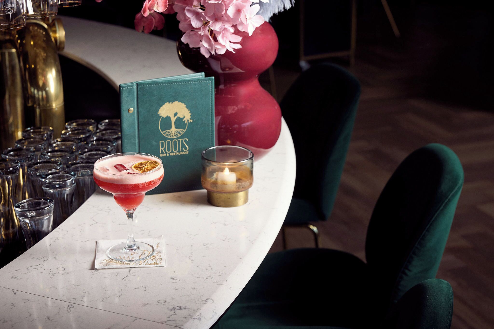 A bar area with a martini glass, a menu, and a candle on a marble countertop.