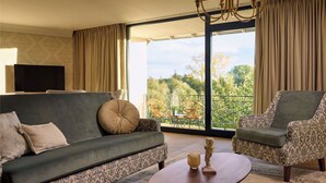 A living room with a sofa, two armchairs, a coffee table, and a TV. - Van Der Valk Hotel Melle - Osnabrück (Melle)