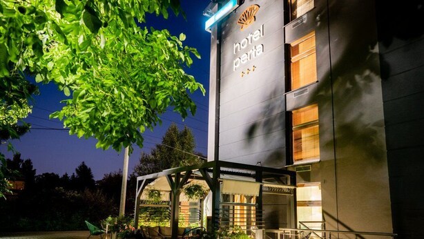 A hotel entrance with a sign reading "hotel perta," a covered outdoor seating area, and a staircase leading to the entrance. - Hotel Perla (Kraków)