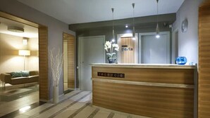 A reception area with a wooden reception desk, a potted plant, and a sign that reads "perla." - Hotel Perla (Kraków)