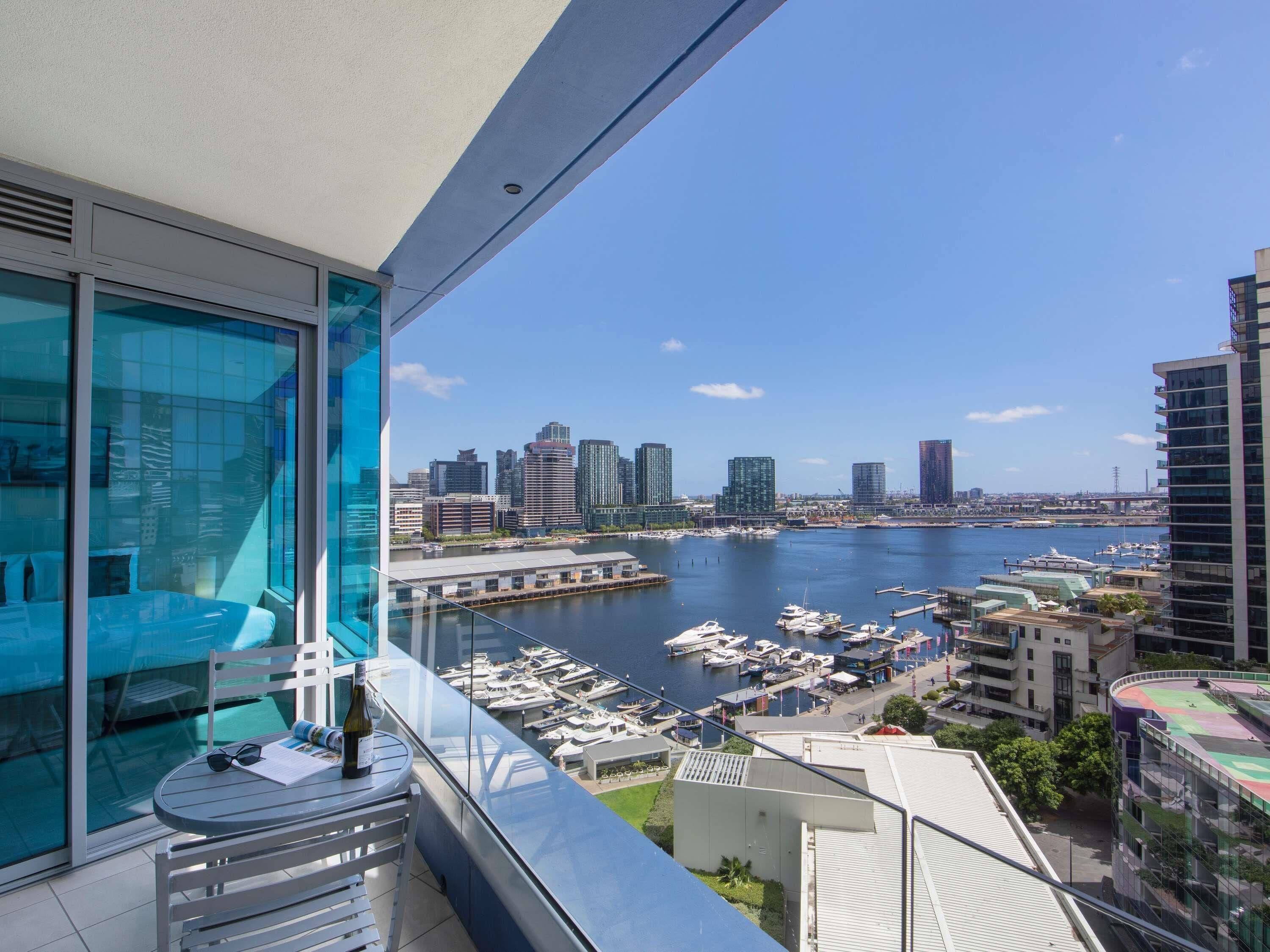 A balcony with a view of a marina and city skyline.