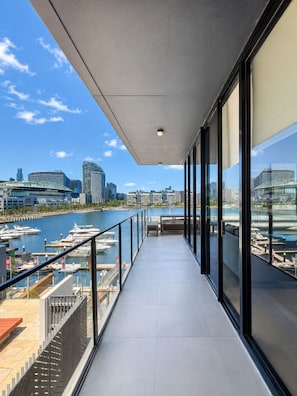 A modern balcony with a view of a marina and city skyline.