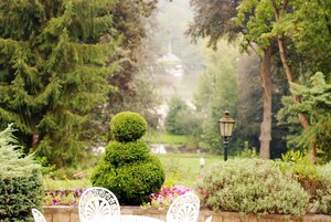 Un jardín con setos bien cuidados, un farol y una vista distante de un edificio.