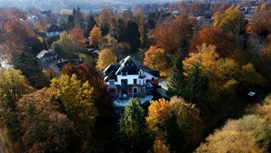 Vue aérienne d’une grande maison entourée d’un feuillage automnal.