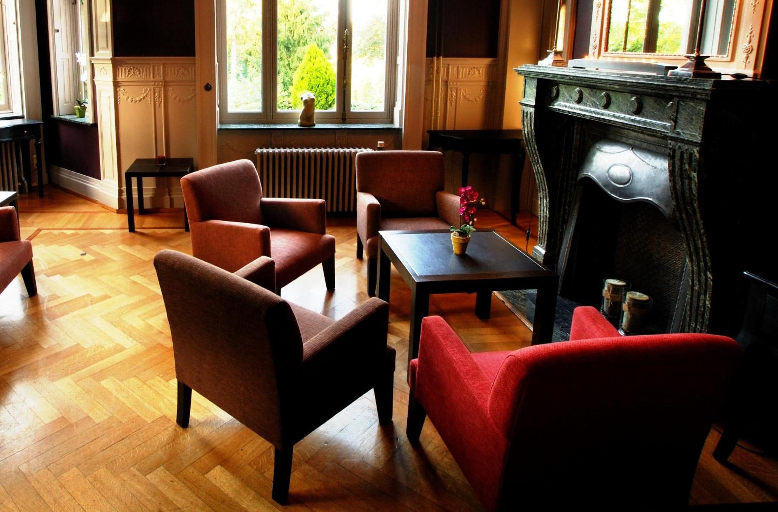 Une pièce dotée d’un plancher en bois, d’une cheminée et d’un mobilier comprenant des fauteuils et un canapé.