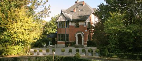 A two-story house with a brick facade, a gabled roof, and a front entrance with steps.