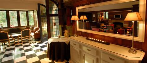 A checkered floor, a large mirror, and a seating area with chairs and a table.