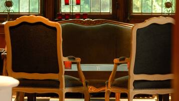 A room with a checkered floor, two ornate chairs, a bench, and a window with stained glass.