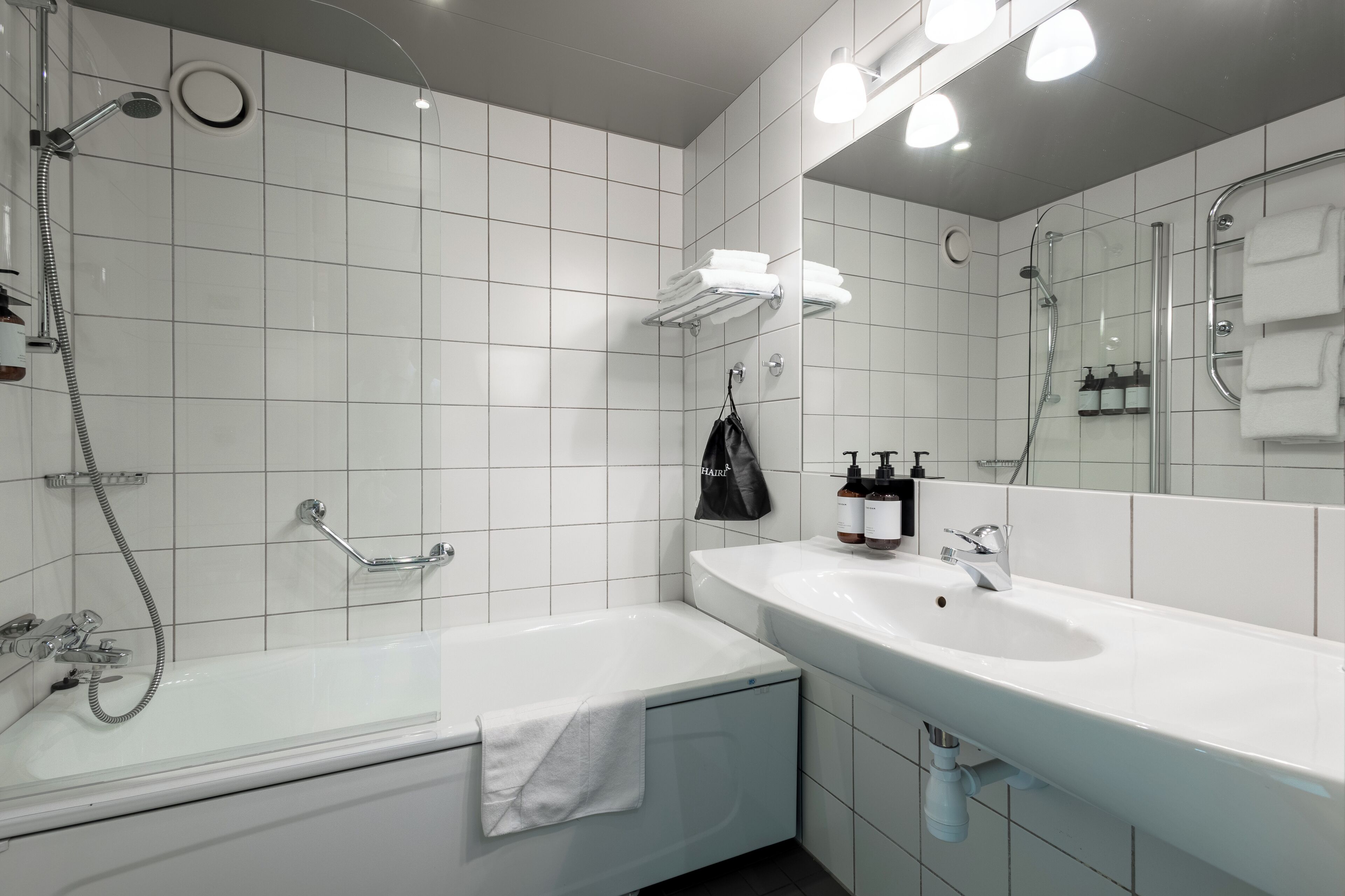 A modern bathroom with a bathtub, a large sink, and a mirror.