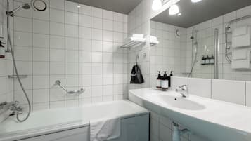 A modern bathroom with a bathtub, a large sink, and a mirror.