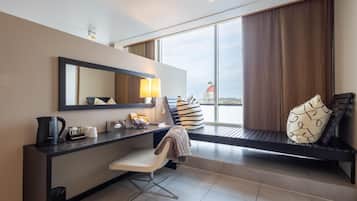 Habitación de hotel moderna con escritorio, silla y un amplio ventanal con vistas a la ciudad.