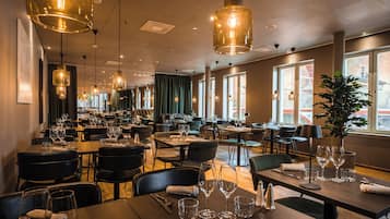 A restaurant with multiple dining tables, chairs, and hanging pendant lights.