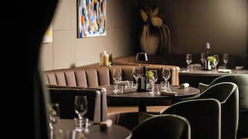 Un restaurante con zona de cabinas, mesas redondas y un florero con flores en la mesa.
