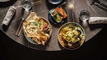 Una mesa de comedor con platos de comida, cubiertos y vasos.