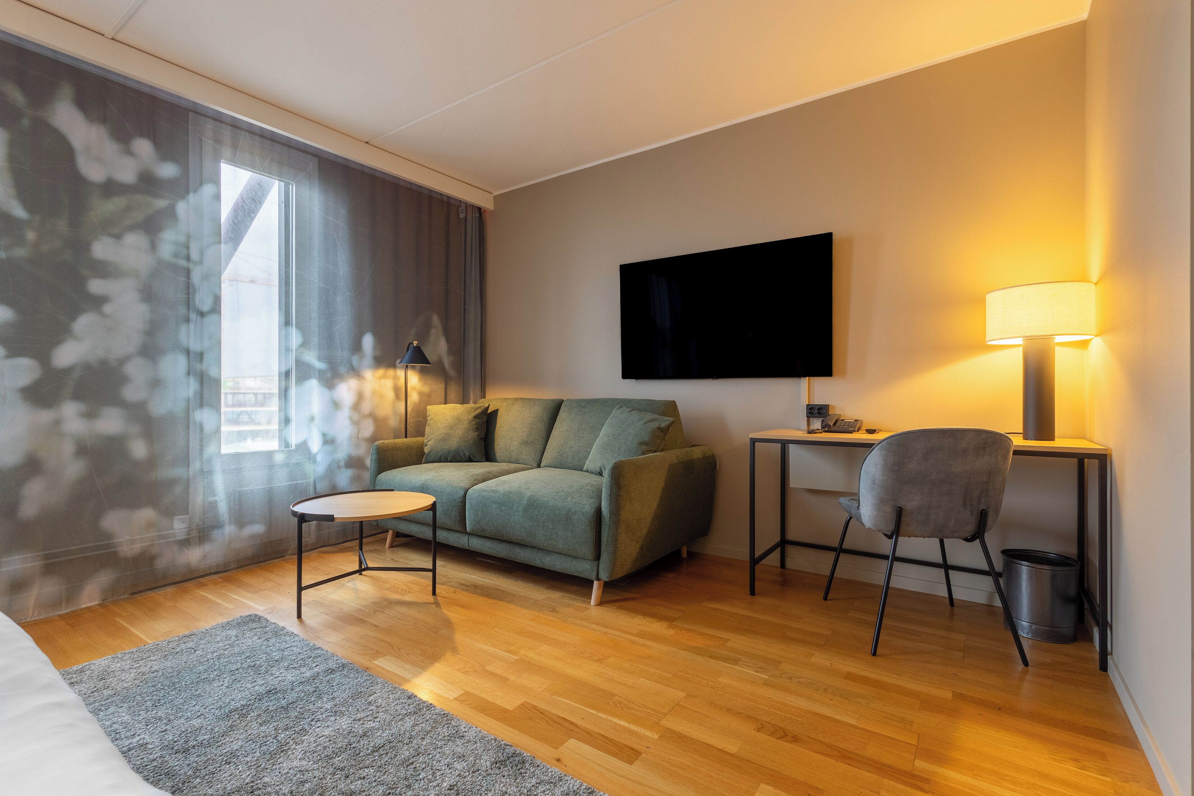 Una sala de estar moderna con un sofá, una mesita, un sillón, un televisor y una lámpara.