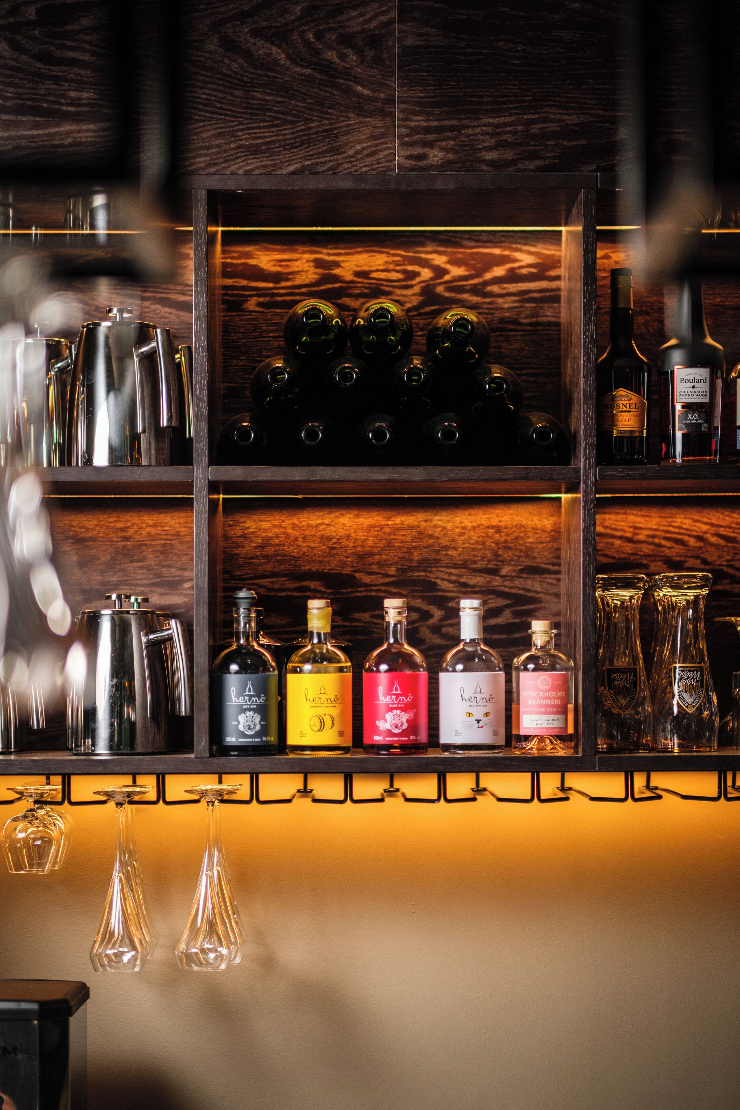 Uma área de bar com prateleiras exibindo diversas garrafas e copos.